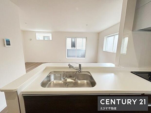 キッチンからリビング全体を見渡せる開放的な設計です。大きな窓から自然光が差し込み明るい空間が広がります。清潔感のある白を基調としたカウンターで日々の家事も快適に進みます。