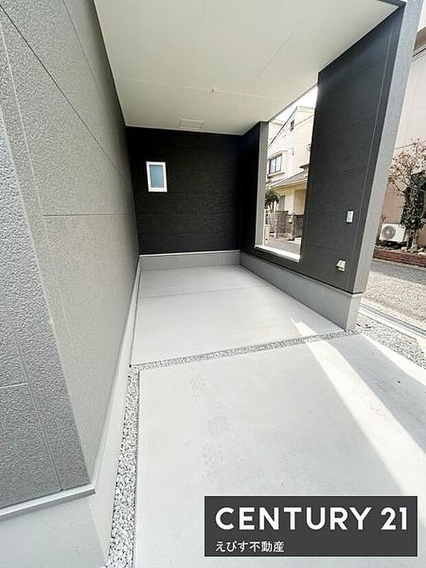 屋根付きの駐車場で車を雨や日差しから守ることができます。コンクリート舗装がすっきりとしています。周囲と調和した外観が印象的です。照明や設備も設置されています。