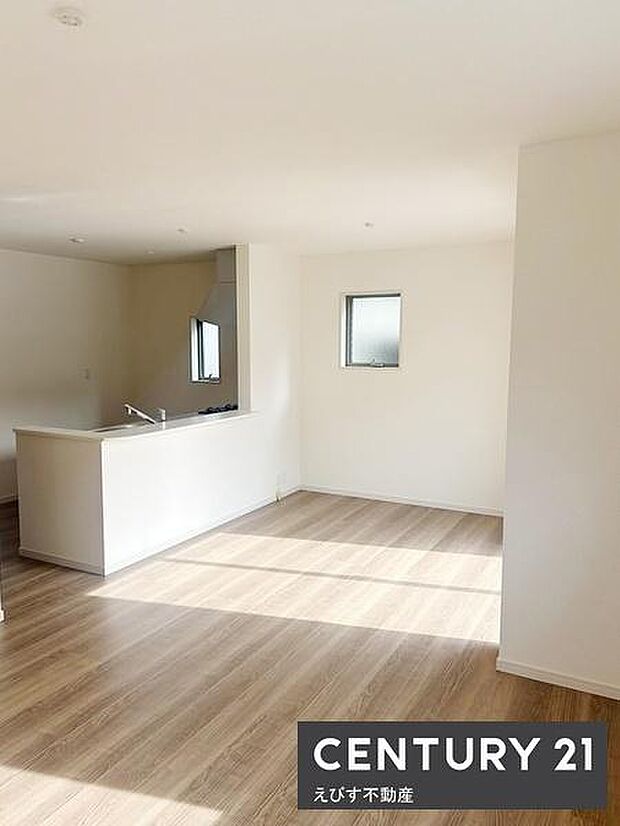 リビングには明るい光が差し込み開放的な空間が広がっています。白を基調とした内装が清潔感を演出しています。床材の色合いが落ち着いた雰囲気を感じさせます。