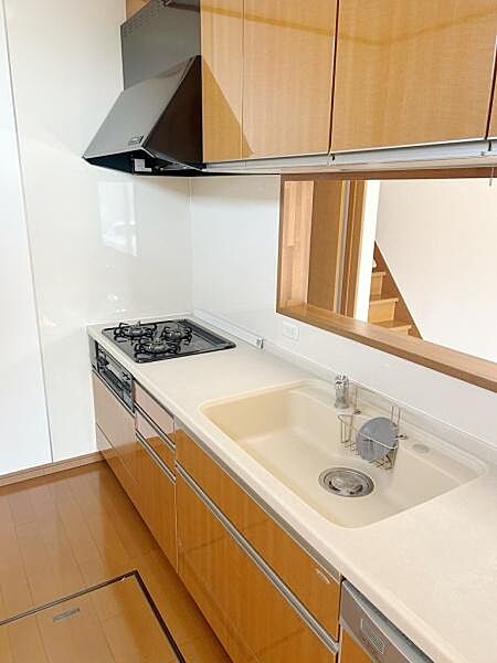 シンプルなデザインのキッチンで使いやすいレイアウトです。収納が豊富で片付けも便利です。カウンター越しにリビングとのつながりも感じられます。掃除がしやすいレンジフードとシンクが設置されています。