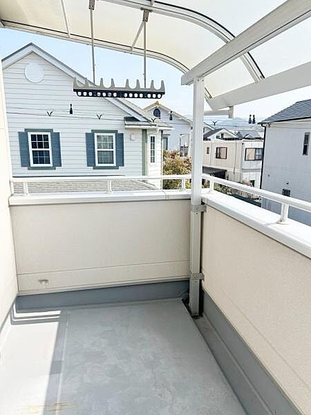 屋根付きのバルコニーで天候に左右されずに利用できます。明るい日差しが差し込む開放的な空間です。物干し金具が設置されており洗濯物を干すのにも便利です。周囲の住宅街の景色を楽しめる見晴らしのある仕様です。