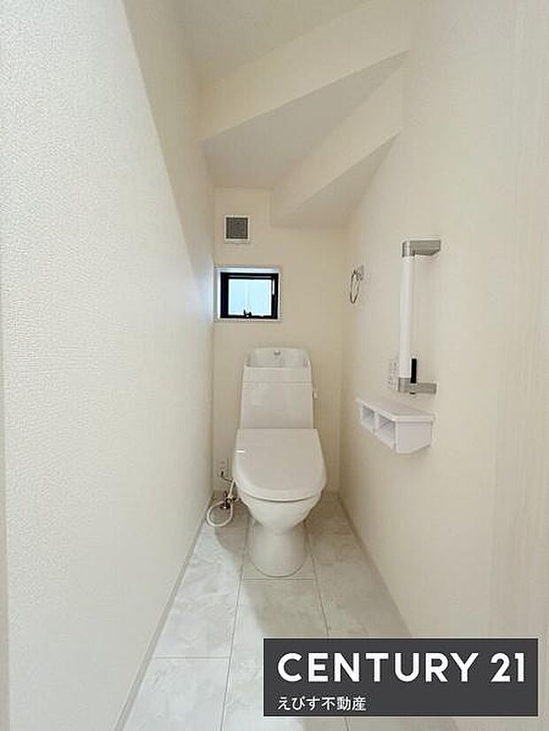 すっきりとした印象のトイレスペースです。明るい色合いで清潔感が感じられます。窓があるため換気もしやすいです。手すりと収納棚が設置されています。段差もなく使いやすいです。