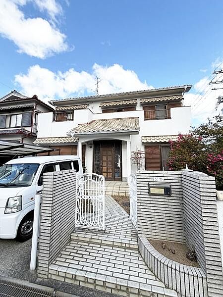 外観は落ち着いたデザインで門扉や塀も統一感があります。玄関アプローチが広く開放感を感じられます。植栽も配置されており彩りが感じられる住まいです。窓やバルコニーもバランス良く配置されています。