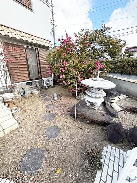 和風の趣を感じる庭には存在感のある石灯篭がアクセントになっています。小道の敷石が自然な雰囲気を演出しています。四季折々の植栽が彩りを添えています。窓から庭への眺めも楽しめる位置にあります。