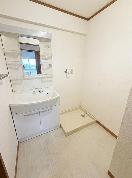 【一部AIモノ消し済み・実際の室内状況優先】シンプルな洗面台と洗濯機置き場が設けられている空間です。明るい内装で清潔感があります。収納スペースも備わっており使いやすさが感じられます。