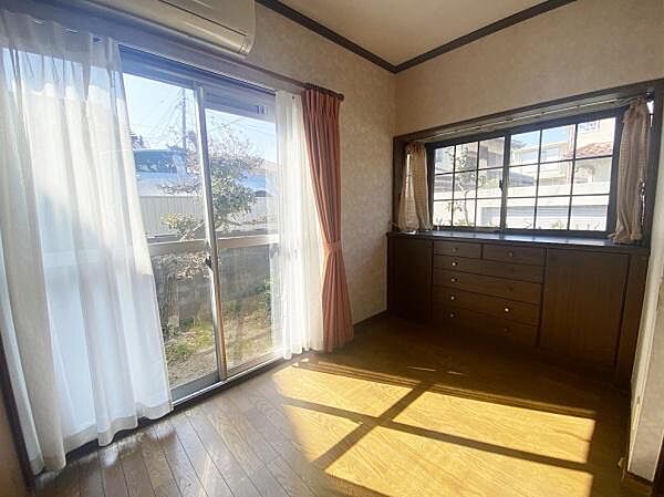 大きな窓から光がたっぷり差し込む明るいリビングです。床は落ち着いた色合いの木目調で室内がすっきり見えます。