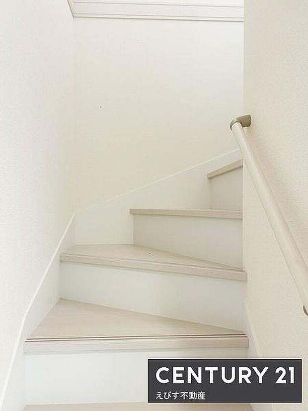 白を基調とした階段で空間が明るく見えます。手すり付きで移動時も安心できます。シンプルなデザインが印象的です。階段幅もゆったりとしています。室内全体との調和が感じられます。