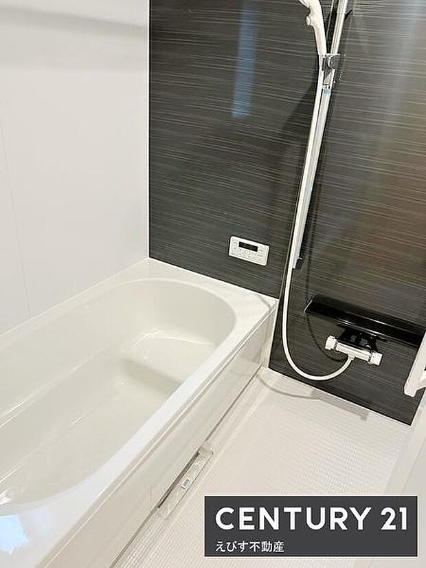 清潔感のある浴槽と洗練されたダーク調の壁で空間に落ち着いた雰囲気を演出しています。浴室乾燥機のスイッチも設置されており使い勝手の良さが感じられます。