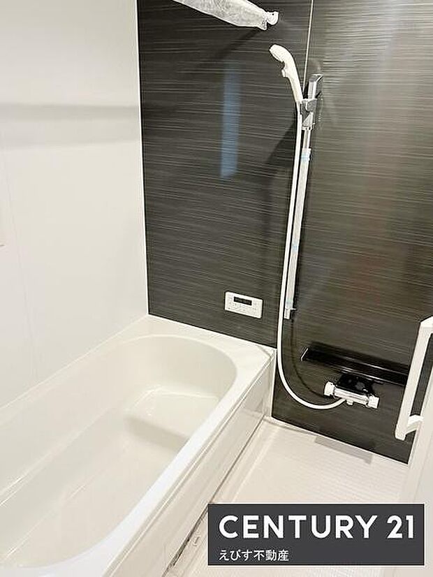 落ち着いたトーンのパネルが特徴的なバスルームです。シャワーと浴槽が機能的に配置されています。清潔感のある空間でお手入れもしやすそうです。浴室のシンプルなデザインが使いやすさを感じさせます。