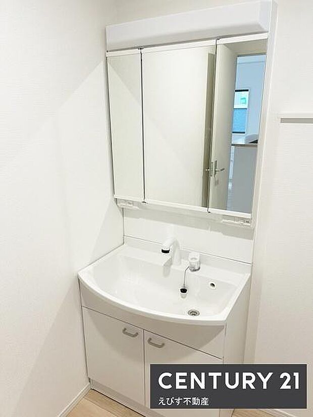 シンプルで清潔感のある洗面台が設置されています。収納スペースも備えられており小物の整理に便利です。鏡は三面鏡仕様で日常のケアもスムーズに行えます。白を基調としたデザインで空間が明るく感じられます。