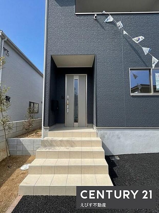 シンプルなデザインの玄関が住まいの印象を引き締めます。玄関ドアはモダンな雰囲気で外壁の色と調和しています。広々とした階段アプローチが出入りしやすく設計されています。