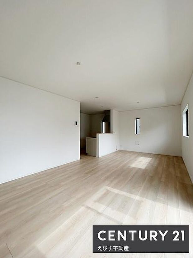 リビングは白を基調とした内装で明るい印象を与えます。大きな窓から自然光が差し込み開放感のある空間です。フローリングが全体に柔らかな雰囲気を演出しています。シンプルで使いやすい設計が特徴です。