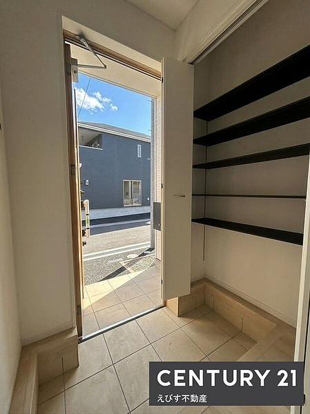 玄関横に設けられた収納スペースは棚の数も豊富で整理がしやすい設計です。扉付きで見た目もすっきり保てます。出入り口からのアクセスも良好です。清潔感のある空間が印象的です。