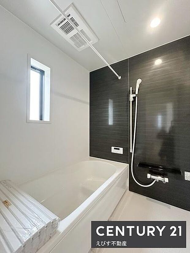 浴室全体が明るく白と黒のコントラストがモダンな印象を演出しています。窓があり換気や採光に配慮されています。広々としたバスタブでリラックスできます。シャワー設備も充実しています。清潔感のある空間です。