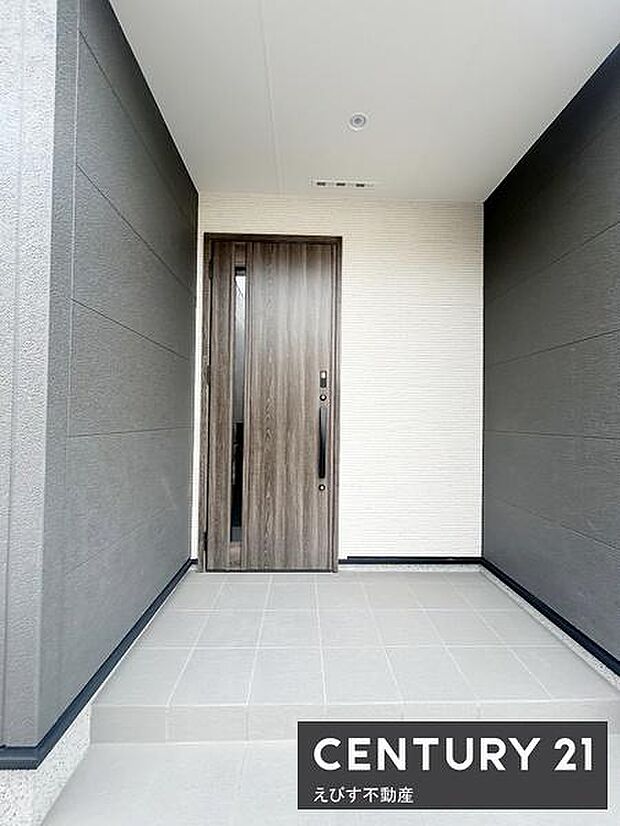 玄関にはシンプルで現代的なデザインが採用されています。木目調のドアがアクセントとなっています。明るいタイル張りの床が清潔感を演出しています。空間にゆとりを感じる設計です。