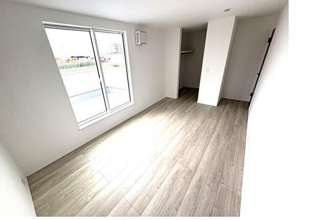 明るい光が差し込む洋室です。すっきりとしたフローリングが広がり清潔感があります。二面採光で空間に開放感があります。収納スペースも確保されています。シンプルなデザインが特徴です。