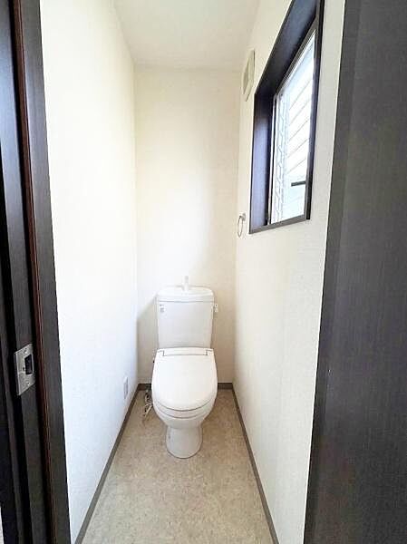 【一部AIによるモノ消し済み】清潔感のあるトイレはシンプルで使いやすい設計です。窓があり自然光が差し込む明るい空間となっています。十分なスペースが確保されています。