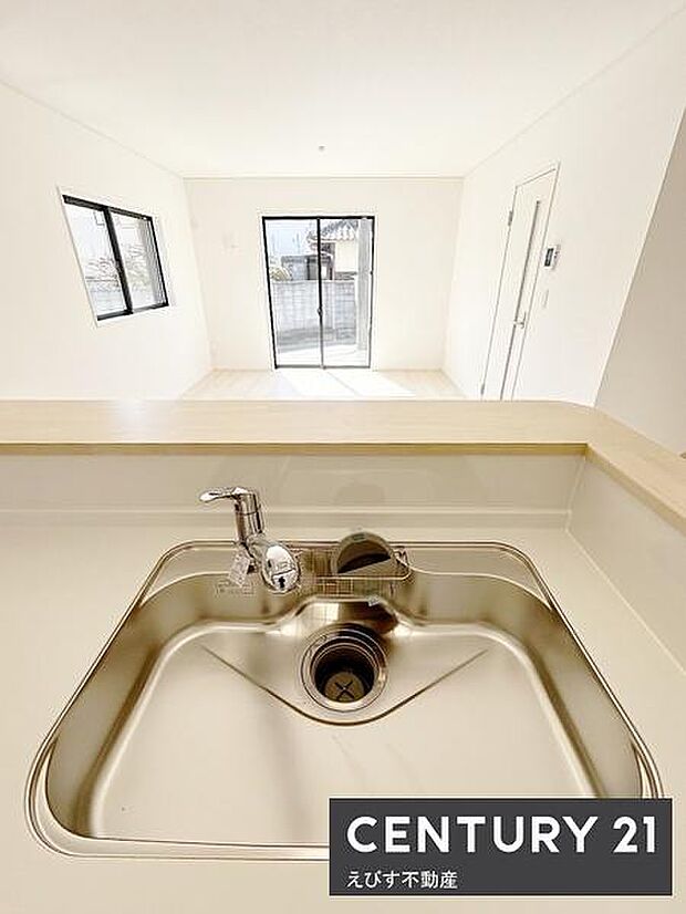 明るい空間に設けられたキッチンは開放感のある設計です。窓から自然光が差し込みます。シンプルなシンク周りで清掃も簡単です。リビングと一体感のある配置が特徴です。快適な生活空間を演出します。