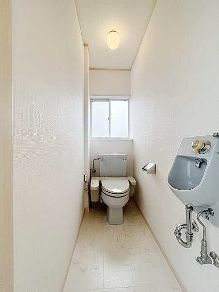 トイレは快適な温水洗浄便座付。すっきりと清潔感のあるトイレ空間です。換気に便利な窓が設置されています。床や壁はシンプルなデザインで手入れがしやすい構造です。明るい照明により快適な印象です。