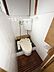 トイレ：木目調の床がアクセントとなっているトイレ空間です。壁面には白いタイルが施されシンプルで清潔感があります。上部には小窓があり換気対策も考慮されています。