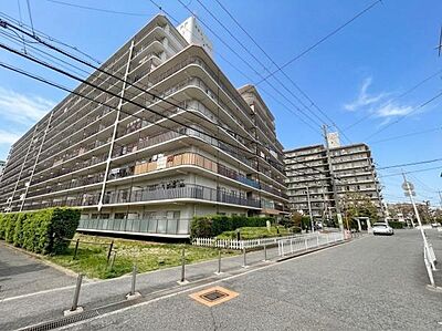 外観：青空のもとに堂々とそびえる大規模マンション。緑豊かな植栽に囲まれた落ち着きのある外観が魅力です。前面道路が広く、車の出入りもスムーズ。ゆとりある快適な住環境での暮らしをご提供いたします。