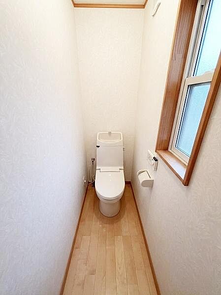 【一部AIによるモノ消し済み】トイレは快適な温水洗浄便座付 。窓付きのトイレなので換気がしやすいです。床や壁が明るい色合いで清潔感のある空間です。