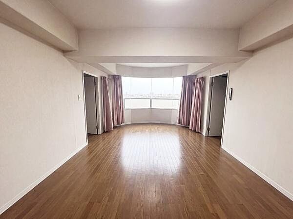 【一部AIによるモノ消し済み】リビングはワイドな窓から明るい光が差し込む空間です。床の木目が温かみを感じさせ落ち着いた雰囲気となっています。天井が高く圧迫感がありません。