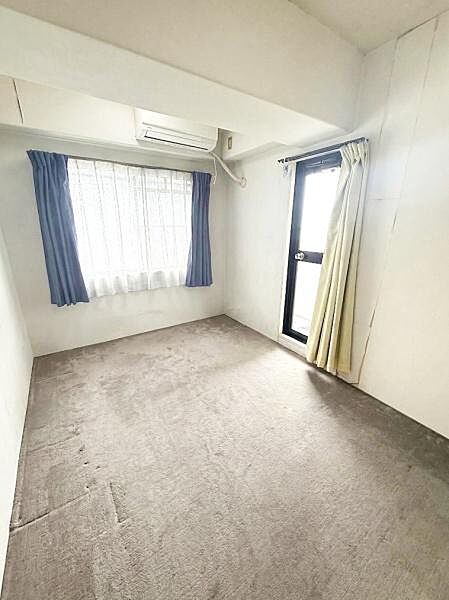 【一部AIによるモノ消し済み】2面に窓を備えた角部屋タイプの洋室。異なる方向から自然光が差し込み、日中は明るく風通しも良好。カーペット敷きで足元も温かく、落ち着いた居室です。