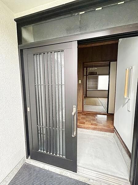 【一部AIによるモノ消し済み】玄関の引き戸はスムーズな出入りをサポートします。段差の少ない設計が日々の使いやすさを実現。玄関スペースは明るく開放的な印象です。