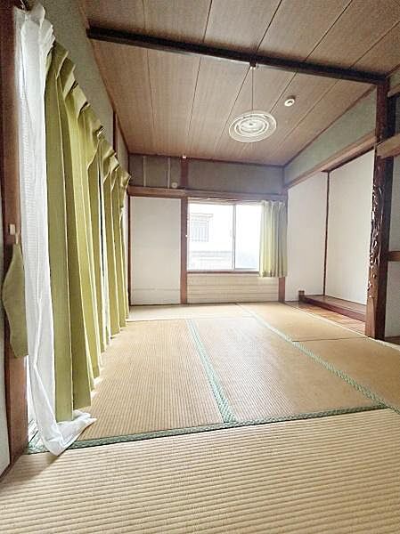 【一部AIによるモノ消し済み】落ち着いた色合いの畳が広がる和室です。大きな窓から自然光が差し込みます。天井や柱の木目も印象的です。