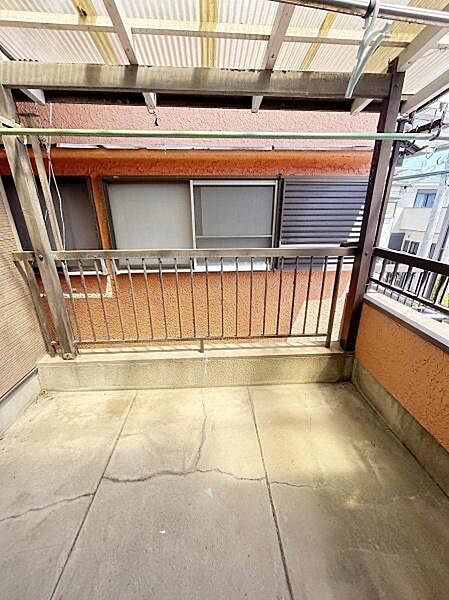 屋根付きのバルコニーで天候に左右されにくい空間です。手すりや物干しが備わっており日差しも感じられます。周囲の建物との距離感も確保されています。コンクリート床でお手入れがしやすい仕様です。