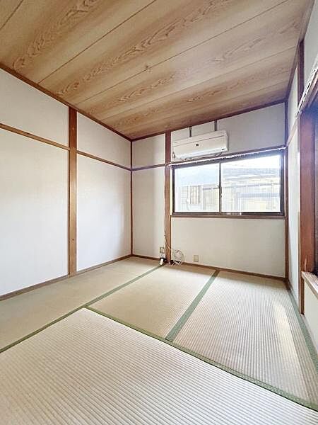 畳の落ち着いた雰囲気が広がる和室です。大きな窓から光が差し込み明るい空間となっています。天井や柱の木目が温かみを感じさせます。エアコン設置済みで快適に過ごせます。収納スペース付きで整理整頓も便利です。