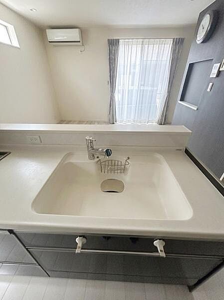 【一部AIモノ消し済み・実際の室内状況優先】広々としたカウンター一体型のシンクが特徴的です。室内に窓があり採光も良好です。収納スペースも充実しているキッチンです。
