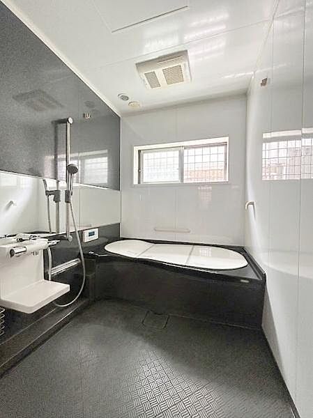 【一部AIモノ消し済み・実際の室内状況優先】窓付きで換気に配慮されたバスルームです。浴槽と洗い場が広々とした設計になっています。シックな色合いの壁が落ち着いた雰囲気を演出しています。