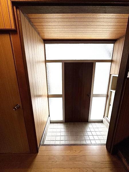 木目調の壁と天井が落ち着いた印象を与える玄関です。ガラス面からやわらかな光が差し込みます。タイル床でお手入れも簡単です。収納スペースも確保されています。