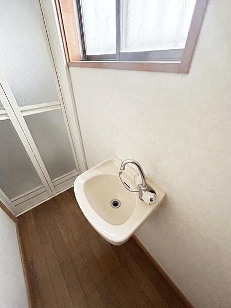 【一部AIモノ消し済み・実際の室内状況優先】窓付きの洗面所で自然光が差し込む明るい空間です。シンプルなデザインの洗面台が設置されておりお手入れも容易です。コンパクトながらも使い勝手の良さが特徴です。