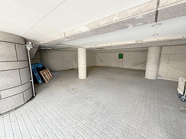 屋根付きの駐車場で雨や風から車を守ることができます。舗装された床面は車の出し入れがしやすい設計です。柱が配置されており区画が分かりやすいです。コンクリートの壁面と天井で清潔感が感じられます。