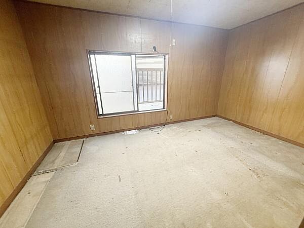 壁全体が木目調のデザインで落ち着いた印象の洋室です。シンプルな内装でお好みに合わせてアレンジしやすい空間です。窓があり通気や採光を確保できます。天井まで高さがあり開放感も感じられます。