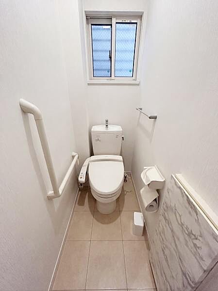 【一部AIモノ消し済み・実際の室内状況優先】手すりが設置されたトイレは利用しやすさを考慮しています。小窓があり採光と換気が可能です。清潔感のある床材とシンプルな内装が空間を整えています。