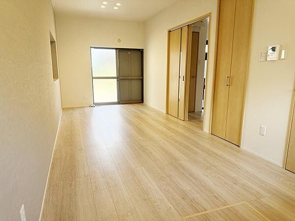 リビングはナチュラルな木目調フローリングが特徴で明るく開放感のある空間です。収納スペースも確保されています。