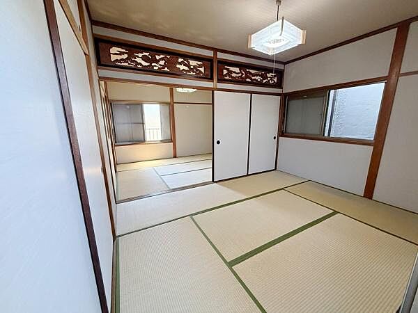和の雰囲気が感じられる落ち着いた和室です。広々とした空間で開放感があります。欄間のデザインも印象的です。障子やふすまの組み合わせが和の趣を引き立てています。大きな窓から自然光が入る明るい空間です。