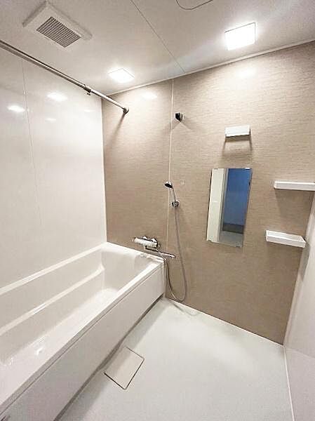 浴室はシンプルで落ち着いた雰囲気の内装です。落ち着いたカラーのアクセントパネルが魅力です。壁面にはミラーと棚が設置されています。
