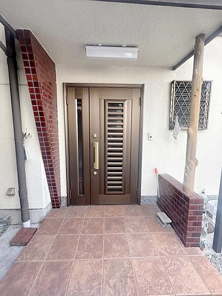 玄関スペースは広めに設けられており使い勝手の良い設計です。タイル張りの床が清潔感を演出しています。シックな色合いのドアが落ち着いた印象を与えます.