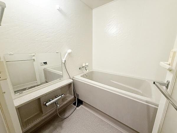 広々とした浴室は日々のリフレッシュに適しています。大きな鏡や使いやすい水栓も魅力的です。シンプルなデザインで清潔感があります。手すり付きで安心してご利用いただけます。