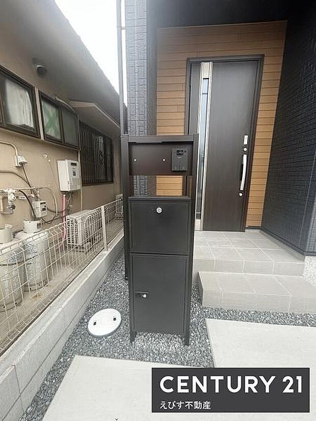 スタイリッシュな玄関ドアが外観に調和しています。宅配ボックス付きで日々の利便性を向上。玄関アプローチは段差が少なく安心です。タイル張りの階段が印象的なアクセントとなっています。