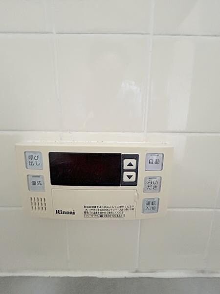 壁面に設置された給湯器リモコンが確認できます。ボタン操作がしやすくシンプルなデザインが特徴です。状態も良好で清潔感があります。
