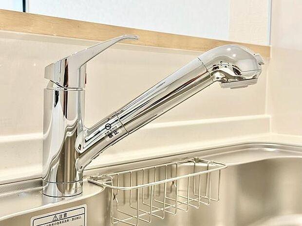 キッチンに設置されたシンプルなデザインの水栓です。ワンタッチで操作でき省スペースな作りになっています。清潔感のあるステンレス素材が印象的です。収納にも便利なラック付きです。
