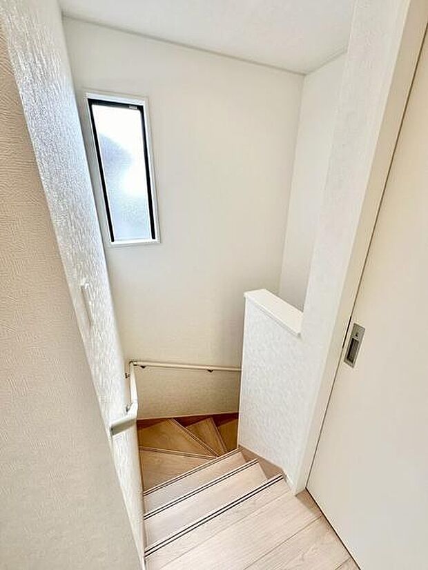 階段スペースに小窓が設けられており自然光が差し込む明るい空間です。白を基調とした内装がすっきりとした印象を与えます。手すり付きで安心して上り下りができます。階段の踏み板も幅広で利用しやすいです。