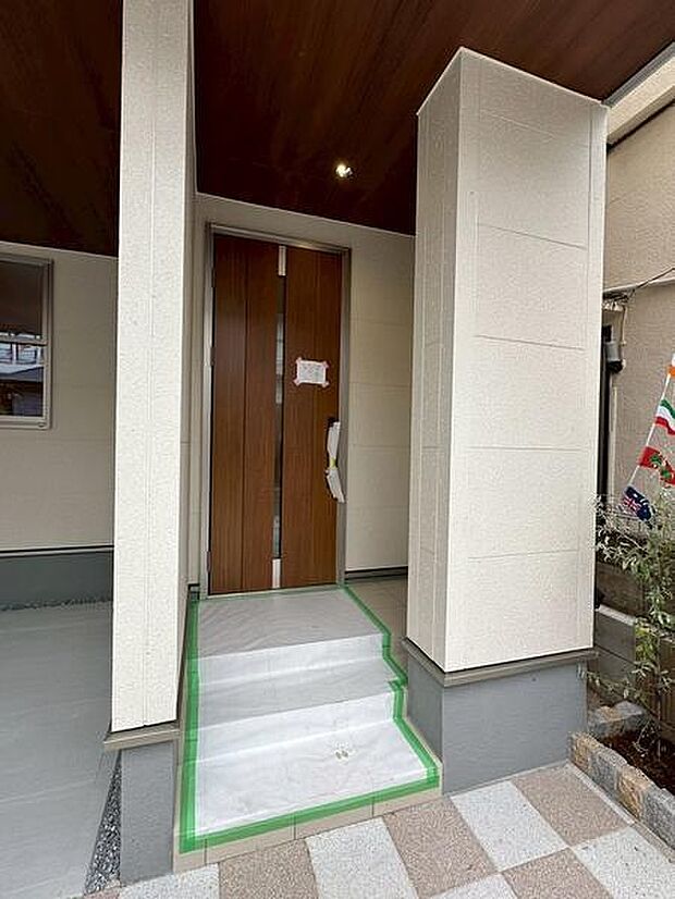 木目調の玄関ドアが住まいに上品な印象を与えます。広々としたアプローチで開放感があります。屋根付きのため雨の日も濡れにくく便利です。階段部分は滑り止め加工がされており安全面にも配慮されています。