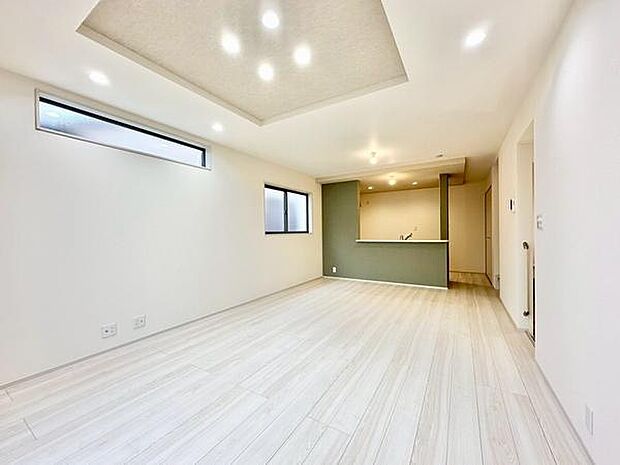 （LDK18帖）明るい色合いのフローリングが広々とした印象を与えるリビングです。天井部分にアクセント照明が配置され空間がすっきりとしています。窓からの自然光も取り入れやすく清潔感のある内装です。